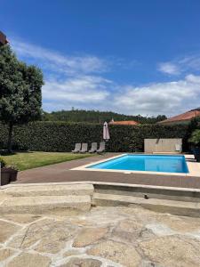a swimming pool with two chairs and an umbrella at Villa dos Amados in Viana do Castelo