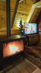een woonkamer met een open haard, een televisie en een kerstboom bij Sarp Bungalov in Kemalpasa