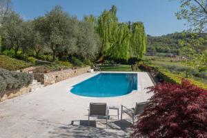 a swimming pool in a yard with chairs and trees at Beautiful villa with private garden and pool in Costermano sul Garda