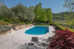 a swimming pool in a yard with chairs and trees at Beautiful villa with private garden and pool in Costermano sul Garda +19 photos