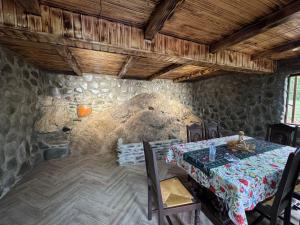 a dining room with a table and a stone wall at Wooden Cottage '' Lailashi '' in Surmushi
