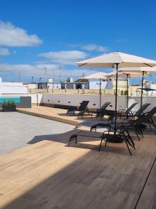 加的斯Apartamentos Soho Boutique Palillero的屋顶上带椅子和遮阳伞的甲板
