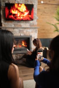a woman taking a picture of a fireplace with her cell phone at Stay in Sapanca in Sakarya