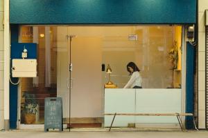 a woman is standing in a store window at まちの別邸 緝 shu in Kochi