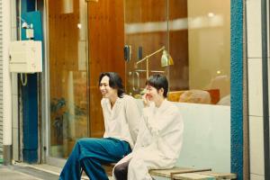 two women sitting on a bench in front of a store at まちの別邸 緝 shu in Kochi