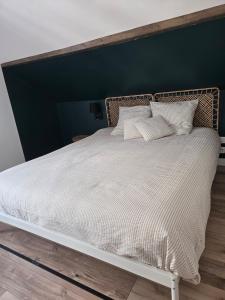 a large white bed with white sheets and pillows at Duplex sous les toits d'Alsace in Dannemarie +4 photos