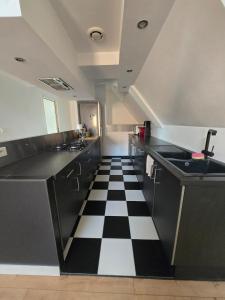 a kitchen with a black and white checkered floor at Duplex sous les toits d'Alsace in Dannemarie