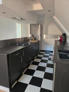 a kitchen with black cabinets and a checkered floor at Duplex sous les toits d'Alsace in Dannemarie