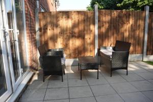 a patio with four chairs and a fence at Town Centre spacious 4 bed town house in Saint Neots