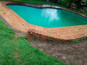 a swimming pool with a wooden boardwalk around it at Green Haven in Benoni