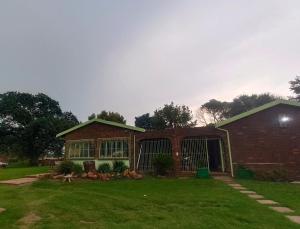 a brick house with a yard with a building at Green Haven in Benoni