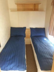 two beds in a small room with blue pillows at 3 Bed Caravan sleeps 8 in Skegness