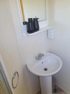 a bathroom with a white sink and a mirror at 3 Bed Caravan sleeps 8 in Skegness +13 photos