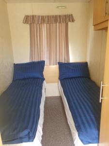 two beds in a small room with a window at 3 Bed Caravan sleeps 8 in Skegness
