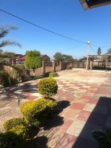 a courtyard with bushes and a fence and a blue sky at Amza guest room in Mogwase