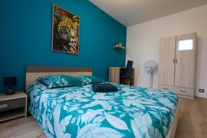 a bedroom with a bed and a blue wall at Chez Viticka in Saint-Vulbas