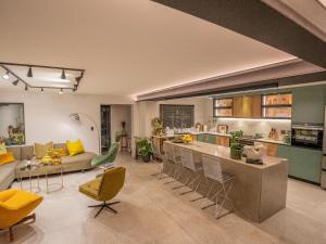 cocina y sala de estar con sillas amarillas y sofá en The Baleia Guesthouse Knysna, en Knysna