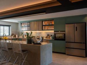 una cocina con armarios verdes y una isla con taburetes. en The Baleia Guesthouse Knysna, en Knysna 8 fotos más