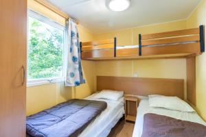 deux lits dans une petite pièce avec une fenêtre dans l'établissement Mobilhome La Clairière, à Saint-Pompont