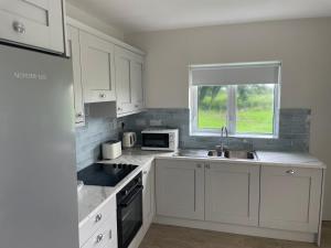 a kitchen with white cabinets and a sink and a window at Corrandulla 2 Storey Home-3 Bedrooms in Galway