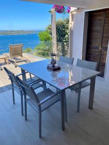 a glass table and chairs with a view of the ocean at Villa Porto vecchio vue mer 5 étoiles piscine parking privé gratuit in Porto-Vecchio