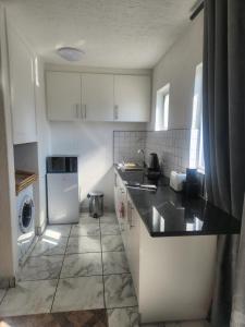 a kitchen with white cabinets and a black counter top at Hayley's inn at village blues in Johannesburg