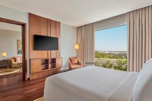 a hotel room with a bed and a television at Courtyard by Marriott Kochi Airport in Nedumbassery