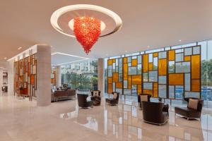 a lobby with chairs and a chandelier in a building at Courtyard by Marriott Kochi Airport in Nedumbassery