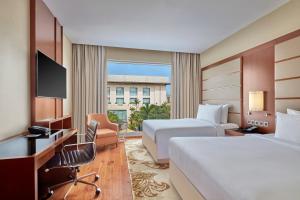 a hotel room with two beds and a desk at Courtyard by Marriott Kochi Airport in Nedumbassery