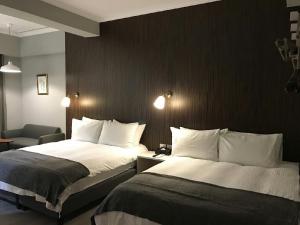 a hotel room with two beds and a chair at 廷海特潮流民宿 漢中館 民宿編號1746 寵物友善陽台房 近微光集與鐵道藝術村 in Taitung City