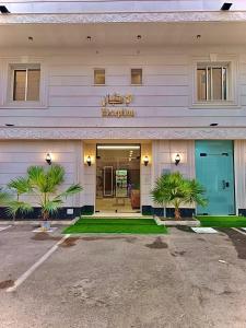 a hotel with palm trees in front of a building at جود المدينة للإجنحة الفاخرة in Medina