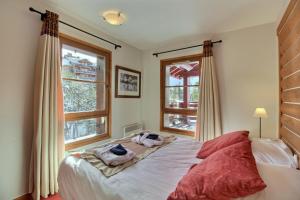 a bedroom with a bed and two windows at ARC 1950 - Appartement 10 personnes Duplex Cheminée - ski aux pieds - Sauna, Hammam, Jacuzzi, Piscine in Arc 1950 +26 photos