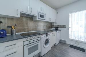 a kitchen with white cabinets and a washer and dryer at Amplio chalet en un entorno natural y tranquilo in San Martín de Valdeiglesias