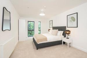 ゴダルマイニングにあるBirchgrove Pepperpot House Exclusively for 65sの白いベッドルーム(ベッド1台、ランプ付)