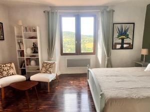 une chambre avec un lit et deux chaises et une fenêtre dans l'établissement Aurifat, à Cordes-sur-Ciel