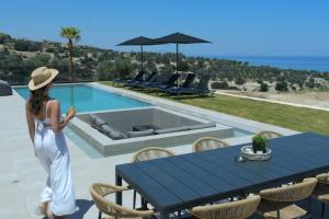 a woman in a white dress standing next to a pool at Villa Andriano in Rethymno