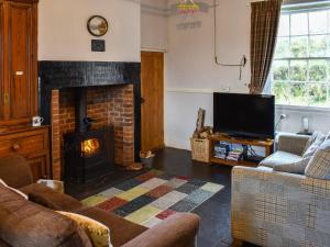a living room with a fireplace and a tv at Harebeck Cottage in Gosforth