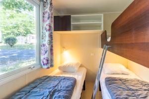 een slaapkamer met twee stapelbedden en een raam bij Mobilhome du Soleil in Saint-Pompont