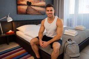 a man sitting on a bed with a backpack at More Than Accommodation in Bratislava