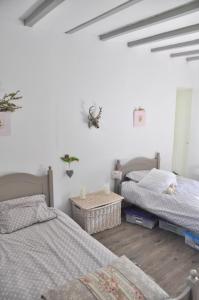 two beds in a room with white walls and wooden floors at Corps de ferme tranquille et familial près de Chambord et de Blois in Séris