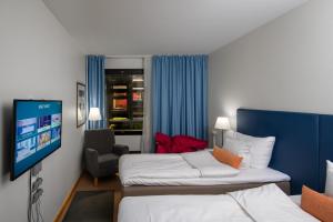 a hotel room with two beds and a flat screen tv at Quality Hotel Sveitsi in Hyvinkää