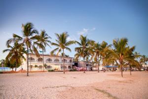 una spiaggia con palme di fronte a un edificio di Hotel Albemarle Galapagos Beachfront a Puerto Villamil