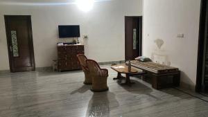 a living room with a table and chairs and a television at Little Haven Haveli - Luxury Heritage Homestay in Bikaner