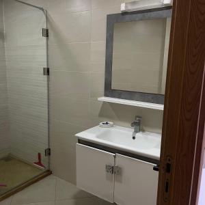 Un baño con lavabo, espejo y ducha. en Appartement familial avec piscine à 900m de la mer Résidence calme, en Bouznika