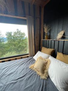 a bed in a room with a large window at La Muzetiere Cabane du crêt in Chamelet