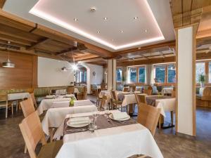a restaurant with white tables and chairs and windows at Haus am Wildbach in Auffach
