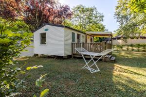 une maison avec une terrasse et une chaise dans la cour dans l'établissement Mobilhome Du Bonheur, à Saint-Pompont