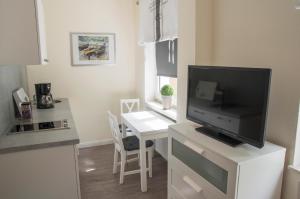 a living room with a tv and a desk with a table at Apartmenthaus Frauenpreiss FeWo 60 in Cuxhaven