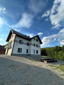 a white house with a black roof on a hill at Dom wypoczynkowy z widokiem na LUBAŃ in Ochotnica Dolna