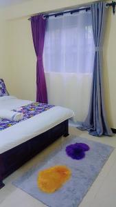 a bedroom with a bed with a rug and a window at Nadelle Cozy Homes in Bonyunyu